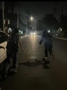 two skateboarders are riding down the street in the dark, with their lights on