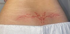 a woman's lower back tattoo with red ink