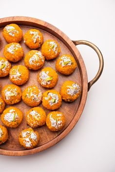 a wooden platter filled with orange cookies covered in powdered sugar