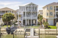 a house on the water next to some houses with balconies and stairs leading up to it