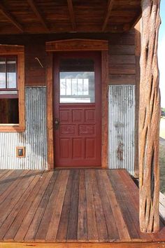 a wooden porch with a red door and window