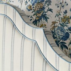 an upholstered bed with blue and white flowers on it