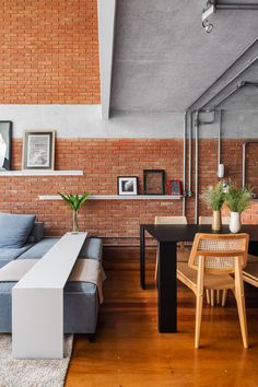 a living room filled with furniture next to a brick wall and wooden floored floors