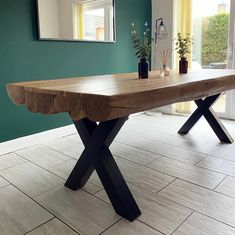 a large wooden table sitting on top of a white tile floor next to a green wall