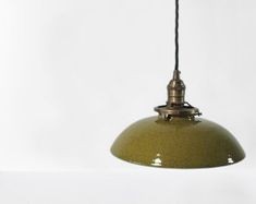 a green hanging light on a white wall