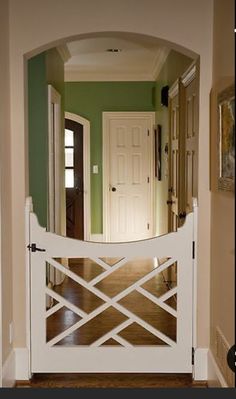 a white gate in the middle of a hallway leading to a door with a mirror on it