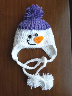 a crocheted snowman hat on top of a wooden table