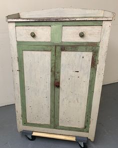 an old green and white cabinet with wheels