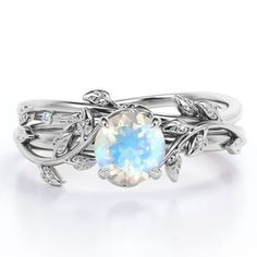 a white gold ring with an opal stone and leaves on the sides, set against a white background