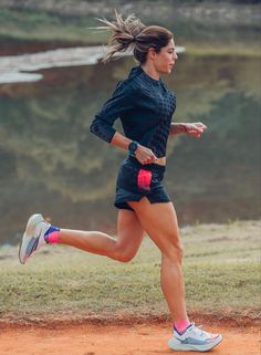 a woman running on a dirt road near water