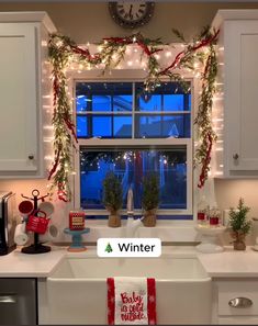 a kitchen window decorated for christmas with lights and garland on the windowsill, along with holiday decorations