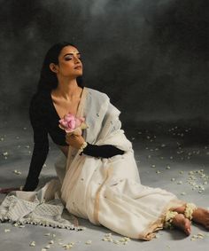 a woman sitting on the ground with flowers in her hand