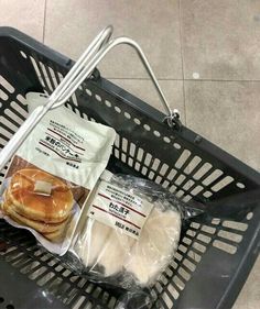 a shopping basket filled with meat and cheeses on top of a tiled floor next to a plastic bag