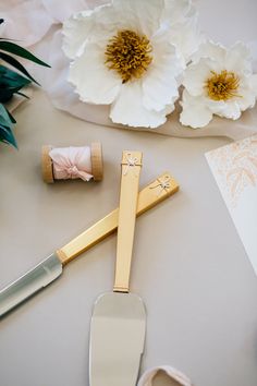 some flowers are sitting on a table next to two knives and a pair of scissors