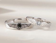 two wedding rings with bats on them are sitting next to each other in white gold