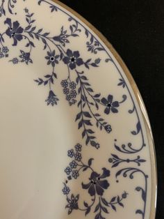 a blue and white plate with floral designs on the rim is sitting on a black surface