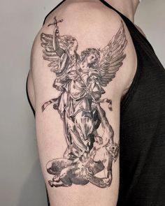 a man with a tattoo on his arm holding an angel and sitting on the ground