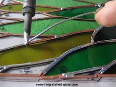 a person is working on some stained glass pieces with a drill in their left hand