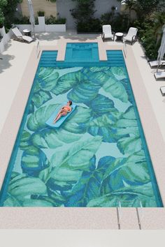 an aerial view of a pool with a person in the water and chairs around it