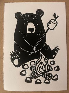 a black and white drawing of a bear holding an apple over a campfire with flames