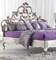 a bed with purple sheets and pillows in a room