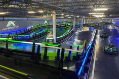 an indoor kart track is lit up with blue and green lights as people ride around