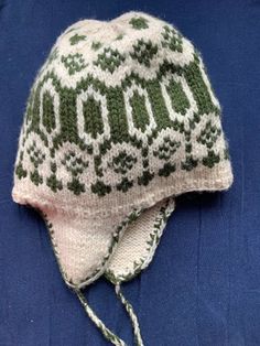 a white and green knitted hat on top of a blue cloth covered in yarn