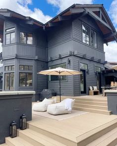 a large gray house with white pillows and an umbrella