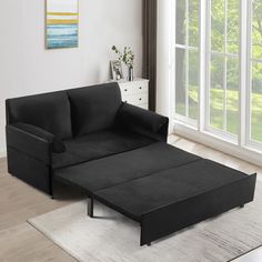 a black couch sitting on top of a rug in a living room next to a window