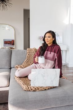 a woman sitting on a couch holding a coffee cup