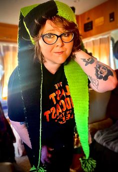 a woman with glasses and a green scarf around her neck is posing for the camera