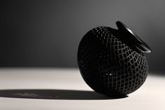 a close up of a black object on a white surface with a shadow from the background