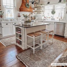 a kitchen with white cabinets and an island in front of the stove top is filled with pots and pans