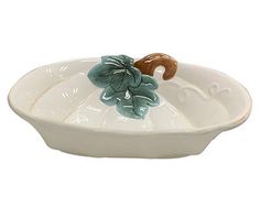 a white bowl with green and brown flowers on the rim, sitting in front of a white background