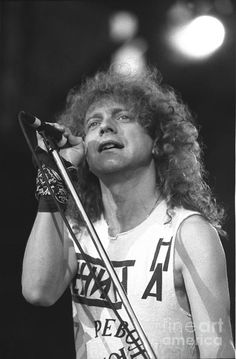 an old black and white photo of a man with long hair singing into a microphone