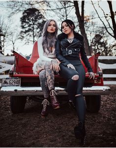 two women sitting on the back of a pickup truck