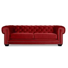 a red couch with buttons on the back and arms, sitting in front of a white background