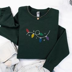 Get ready to shine bright all season long with this festive embroidered Christmas Lights sweatshirt! Featuring a playful tangle of colorful holiday lights stitched with intricate detail, this cozy sweatshirt is perfect for spreading cheer everywhere you go. Made from soft, breathable fabric for ultimate comfort, it's ideal for chilly nights by the fire, decorating the tree, or attending Christmas parties. Whether you're sipping hot cocoa, caroling, or enjoying a holiday movie marathon, this swea Embroidered Christmas, December 24th, Movie Marathon, Holiday Movie, Sweater Gift, Christmas Parties, Holiday Sweater, Cozy Sweatshirts