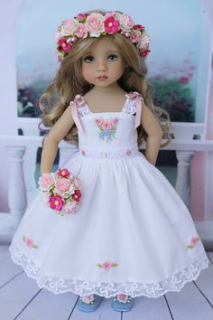 a doll wearing a white dress with pink flowers in her hair