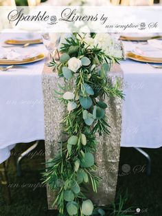 the table is set with white flowers and greenery for an elegant touch to it