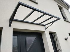 an awning on the side of a house with black doors and window panes