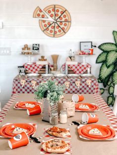 the table is set with orange plates and pizzas