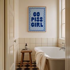 a white bath tub sitting next to a wooden stool under a painting on the wall