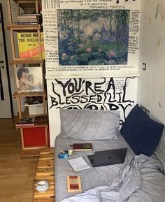 a bed with a laptop on top of it next to a book shelf filled with books