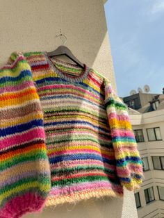 a multicolored sweater hanging on the side of a building