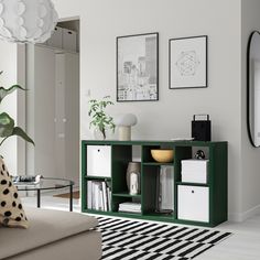 a living room with white walls and green shelving unit in the center, black and white striped rug on the floor