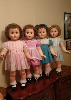 five dolls are standing on top of a dresser