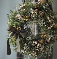 a person holding a wreath with pine cones and berries