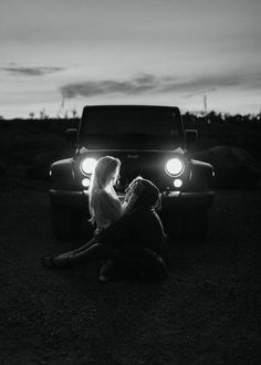 a woman sitting on the ground next to a truck