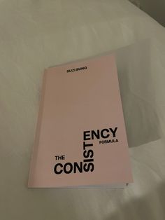 a pink book sitting on top of a white bed covered in sheets and pillows with the title, ency the cons